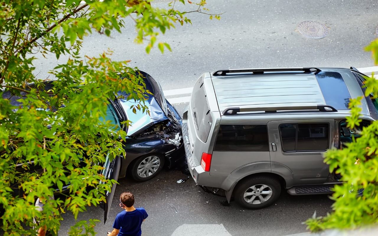 dois carros envolvidos num acidente enquanto condutores se preparam para preencher a declaração amigável