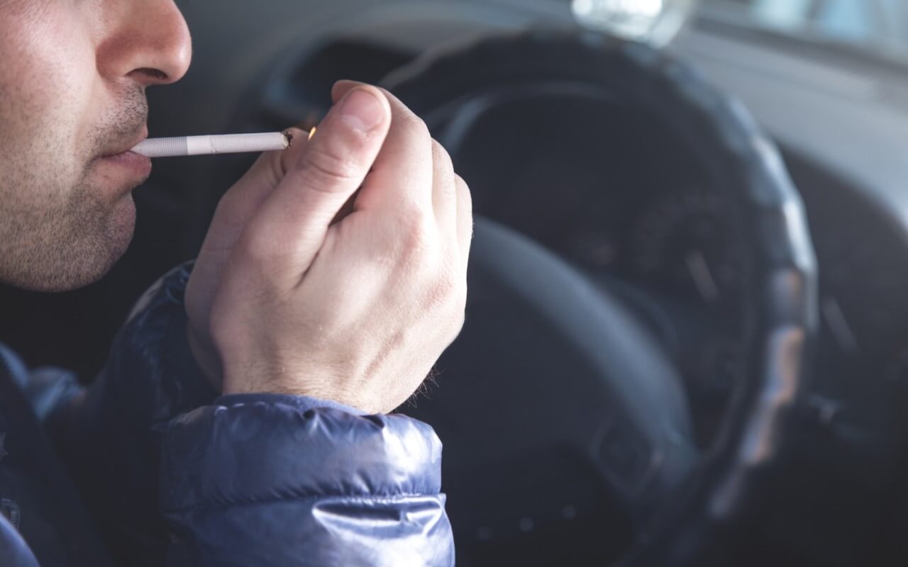 homem a fumar tabaco no carro