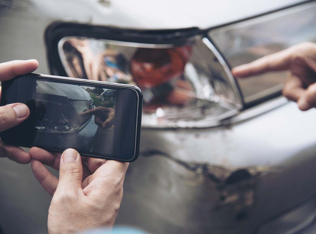 homem a registar danos depois de acidente automóvel